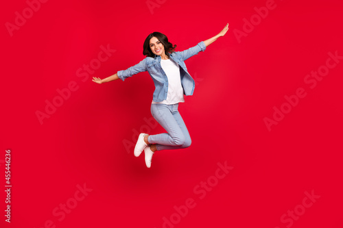 Full length body size view of attractive cheerful girl jumping good mood rest isolated over vibrant red color background