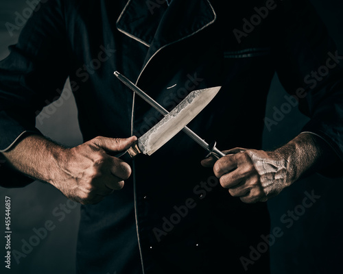Chef sharpening a knife or cleaver on a metal file