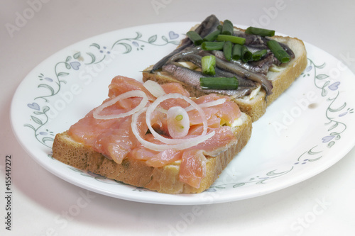 sandwich pair with solted fish: slices of salted salmon and small sprats, on white toast bread, with butter, seasoned with chopped shallots