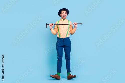 Photo of crazy dancer guy hold cane dance open mouth wear hat suspenders shirt bow tie isolated blue color background