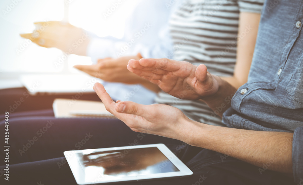 Obraz premium Business people clapping at meeting or conference, close-up of hands. Group of unknown businessmen and women in sunny office
