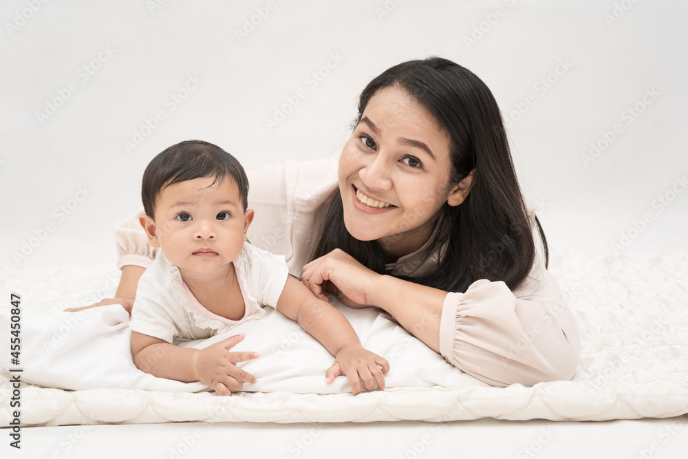 Asia mother and daughter lay together on the bed smiling and enjoying each other. Asia mother and daughter lay together on the bed smiling and enjoying each other.