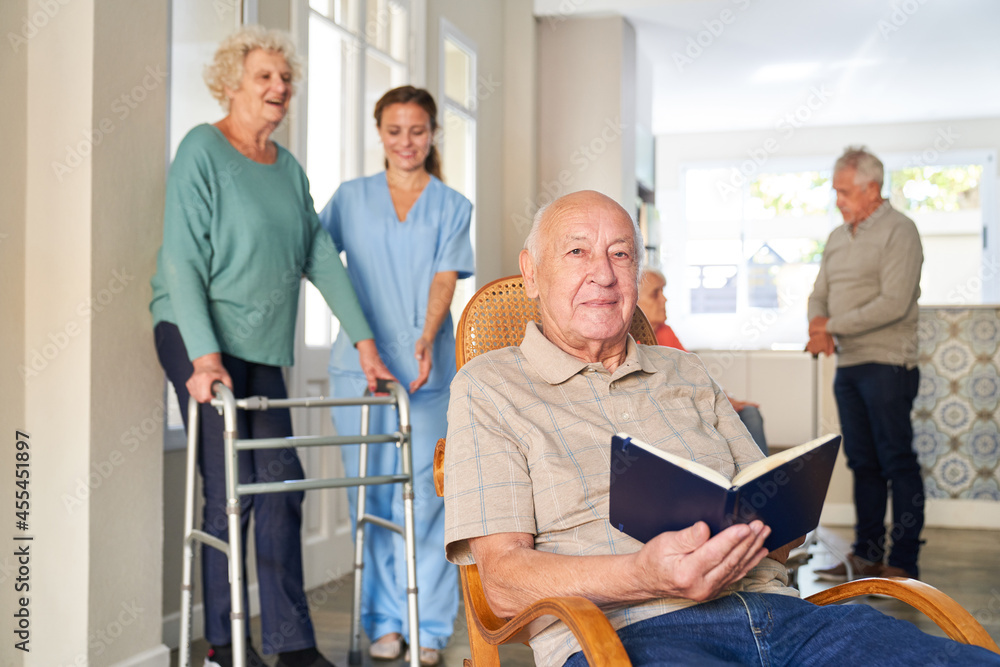 Obraz premium Senior mit Buch in einem Sessel in einem Seniorenheim