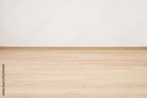 Empty wooden floor with white concrete wall.