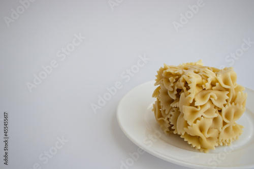 Cooked farfallini pasta in a shape of cube on a white plate. Copy space.