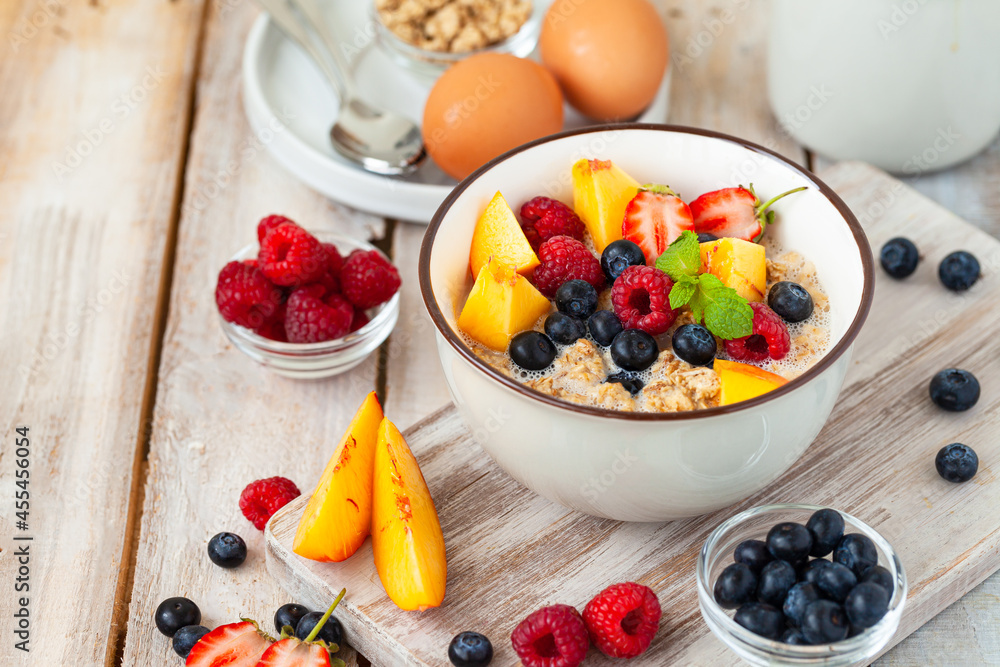 Bowl with vegan granola with fresh ripe organic berries, peach, plant milk, mint. Concept of dieting, detox, tasty simple super food, healthy low calories breakfast. Wooden background, close up Bowl with vegan granola with fresh ripe organic berries, peach, plant milk, mint. Concept of dieting, detox, tasty simple super food, healthy low calories breakfast. Wooden background, close up