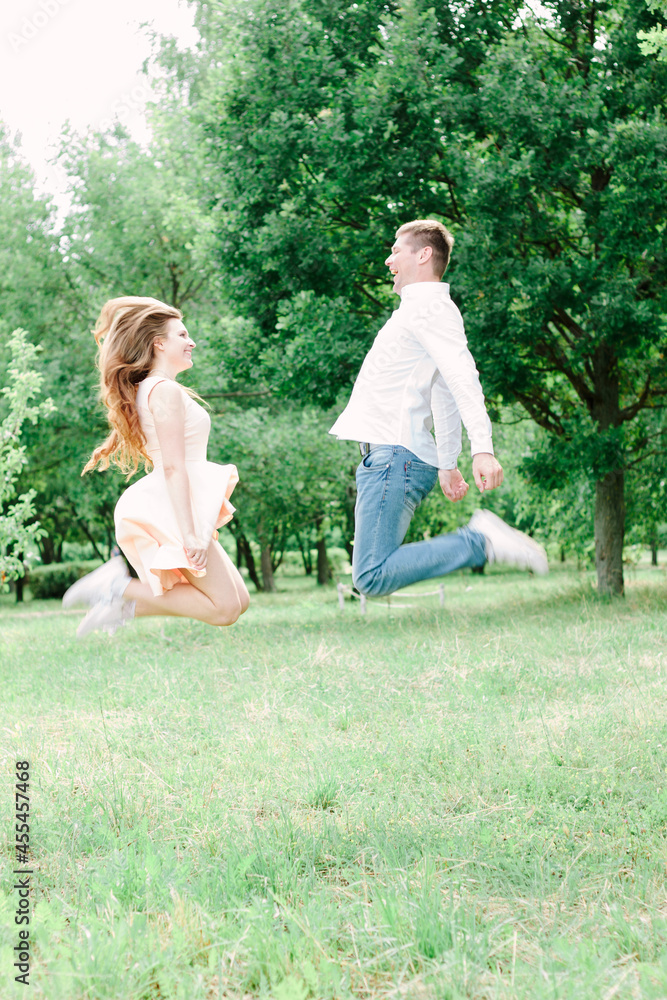 Obraz premium Young couple jumping in the green park
