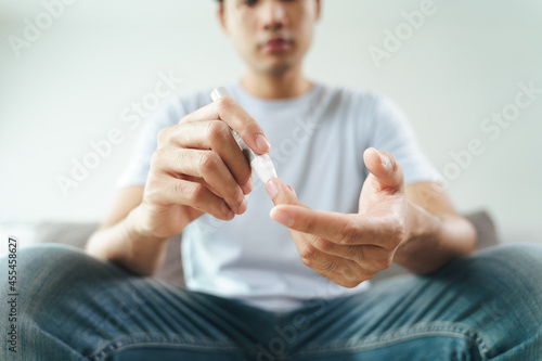 Asian man using lancet on finger for checking blood sugar level by Glucose meter, Healthcare and Medical, diabetes, glycemia concept © Suriyawut