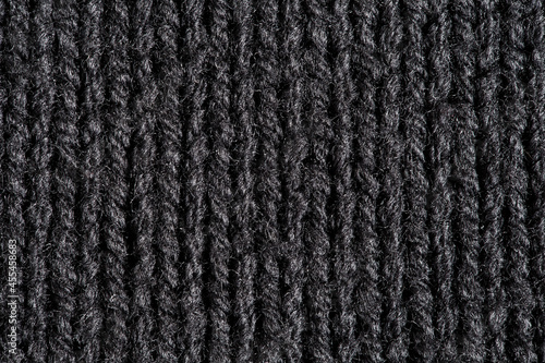 Knitted fabric made of black wool threads, background structure, close-up macro view