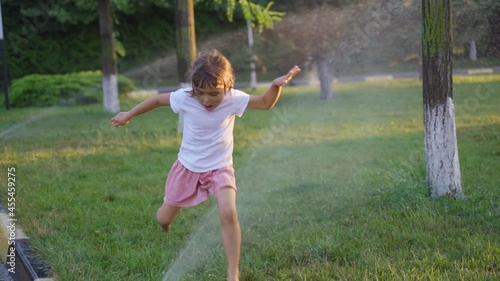 Happy little girls play with a stream of water from a lawn sprinkler. playing outdoors in the backyard lawn children with splashing water having fun together