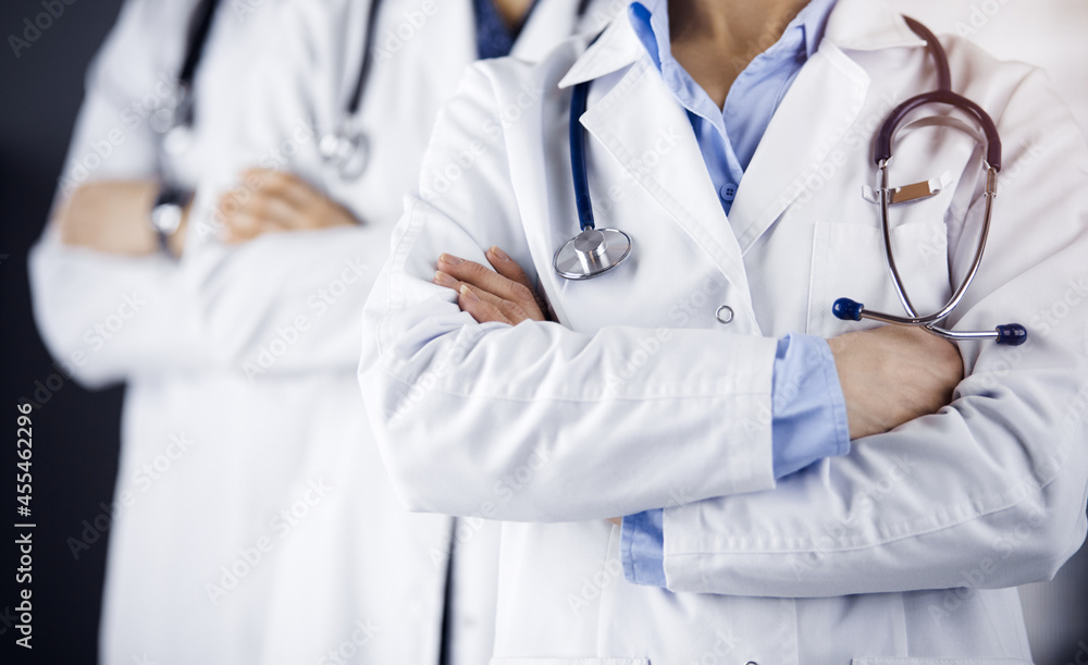 Group of modern doctors standing as a team with arms crossed in sunny hospital and ready to help patients. Medical help, insurance in health care Group of modern doctors standing as a team with arms crossed in sunny hospital and ready to help patients. Medical help, insurance in health care