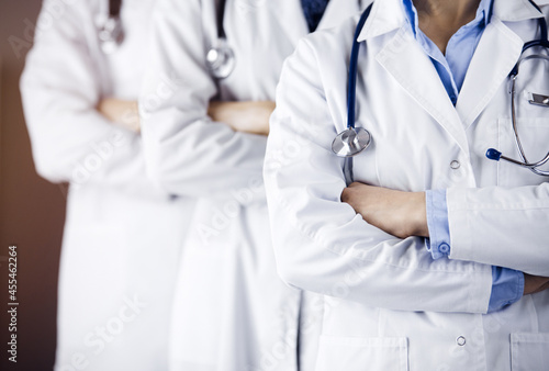 Group of modern doctors standing as a team with arms crossed in sunny hospital and ready to help patients. Medical help, insurance in health care