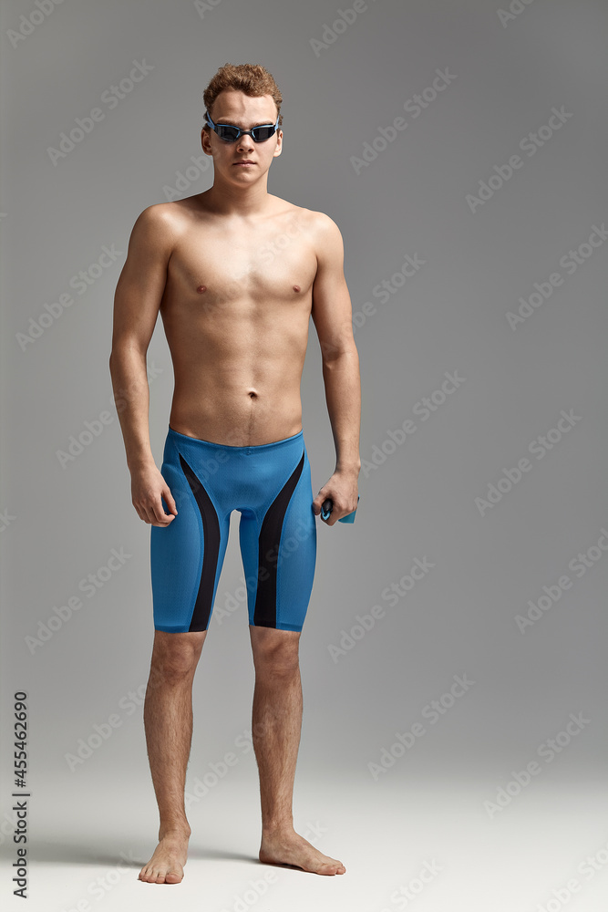 Portrait of a swimmer in a cap and mask, half-length portrait, young athlete swimmer wearing a cap and mask for swimming, copies of space, gray background