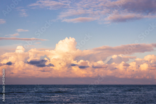 Scenic sunrise over the sea. Morning dusk on island. Dramatic morning sky with clouds. Summer seascape in twilight. Calm sea and idyllic sunrise. Golden sunsine through clouds over sea.