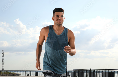 Handsome man in sportswear running outdoors on sunny day © New Africa