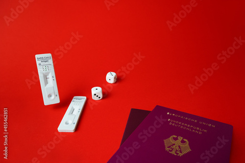 Rapid SARS-Cov-2 Antigen test,negative result,unused,dice on red,pair of german tourist passport.Bad or good luck concept for european traveller crossing border,quarantine.Play fate game,copy space photo