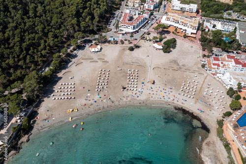 Top down aerial photo of the Spanish island of Ibiza showing the beautiful beach front and hotels on and the beach at Cala Llonga in the summer time in the Balearic Islands, Spain photo