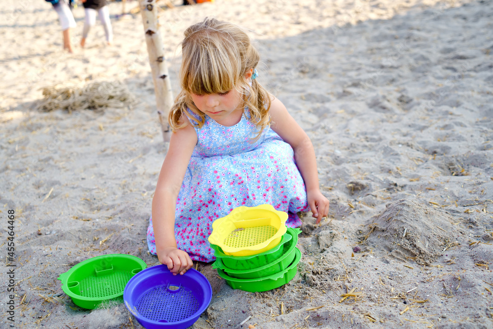 Little preschool girl playing with sand toys on the beach. Cute happy toddler child on family vacations on the sea. Active child having fung on Baltic Sea. Outdoor activity for children Little preschool girl playing with sand toys on the beach. Cute happy toddler child on family vacations on the sea. Active child having fung on Baltic Sea. Outdoor activity for children