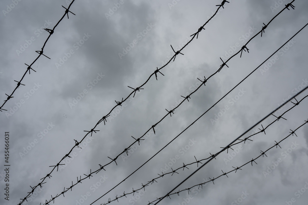 Close-up of barbed wire on gray clouds background. Close-up of barbed wire on gray clouds background.