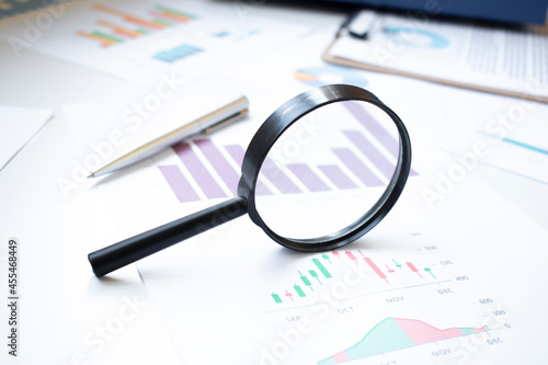 Conceptual Magnifying Glass on Top of Sales Invoice Reports, Emphasizing Scrutinizing Figures.