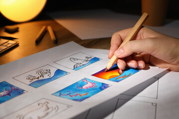 Woman drawing cartoon sketch in storyboard at workplace, closeup. Pre-production process
