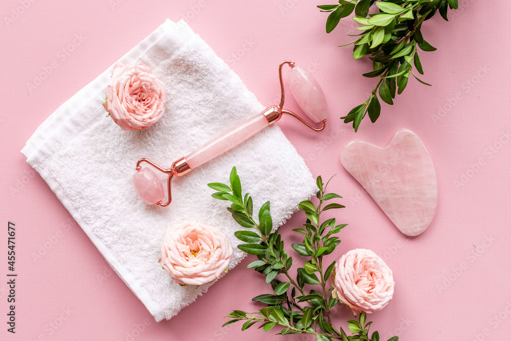 Pink gua sha massage stone and face roller with rose flowers Pink gua sha massage stone and face roller with rose flowers