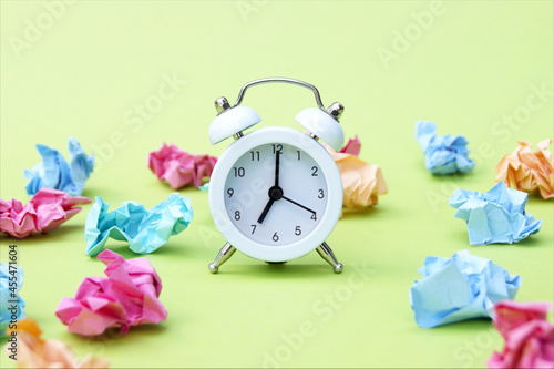 Vintage white alarm clock on a background of crumpled multicolored stickers.