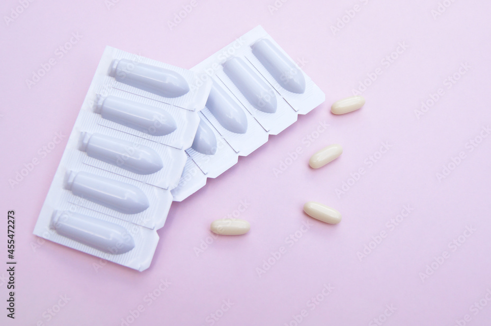Gynecological medicines for women's health in form of suppository, capsules on pink background. Gynecological medicines for women's health in form of suppository, capsules on pink background.