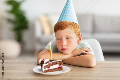 Upset birthday boy looking at lid candle on his cake