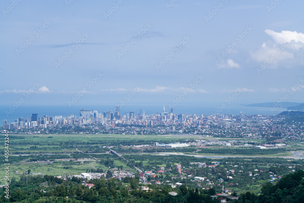 View from the mountain to the city in the bay of the sea on a summer sunny day against the background of a blue sky with white clouds and blue sea