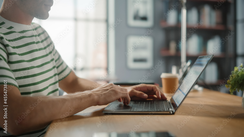 Fototapeta premium Portrait of Handsome White Man Doing Remote Online Work on Laptop Computer while Sitting at his Desk. Freelancer Working From Home. Side View Shot