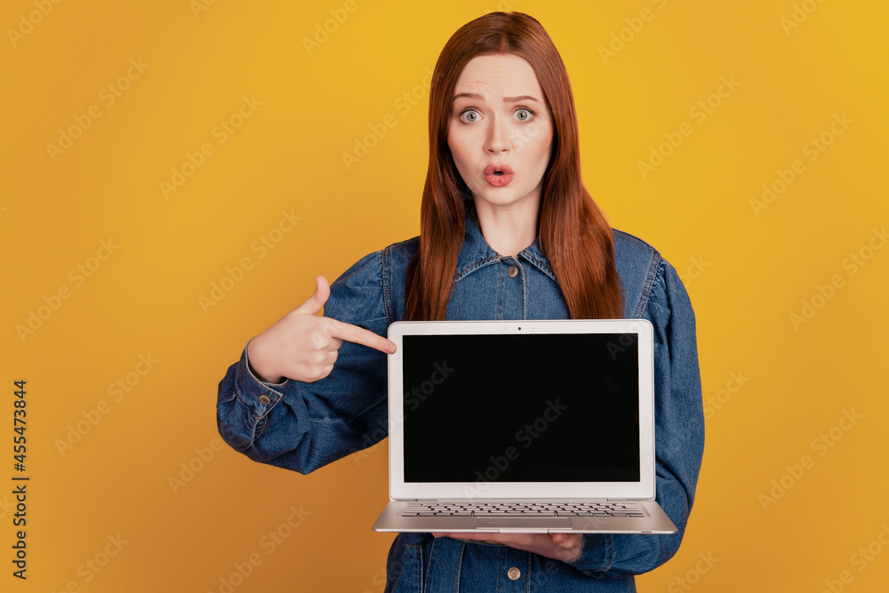 Portrait of funny lady hold netbook direct finger touch screen empty space on yellow background Portrait of funny lady hold netbook direct finger touch screen empty space on yellow background