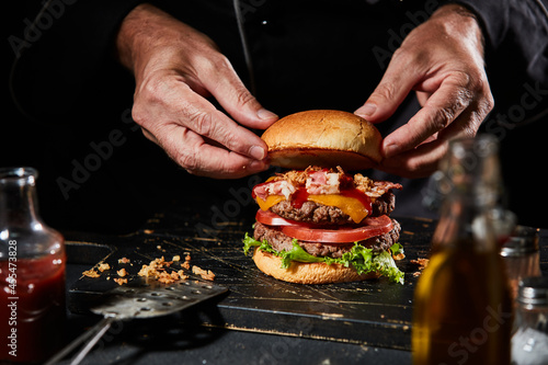 Bild auf Leinwand Chef or cook preparing a gourmet Whopped or double burger