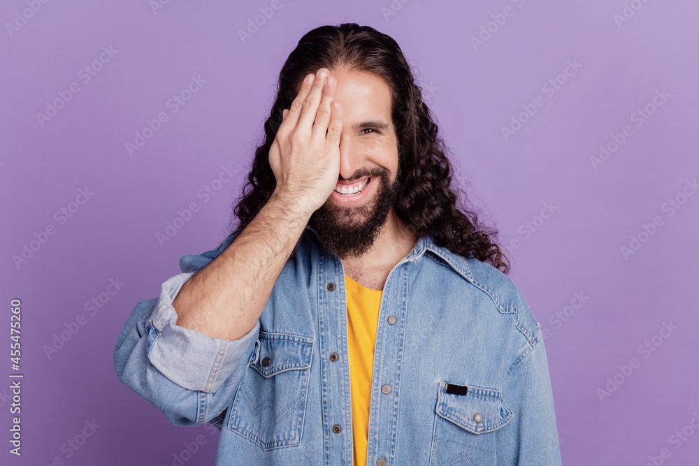 Closeup of happy smiling guy looking at camera hand cover eye half face Closeup of happy smiling guy looking at camera hand cover eye half face