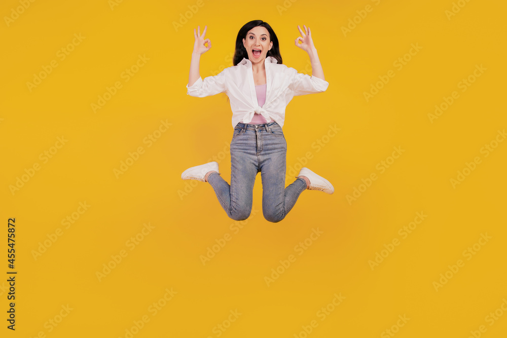 Portrait of funny girl jump show okey signs on yellow background Portrait of funny girl jump show okey signs on yellow background