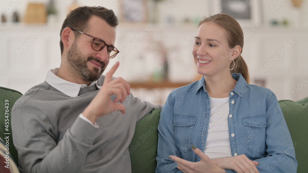 Couple having Conversation while Sitting on Sofa Couple having Conversation while Sitting on Sofa