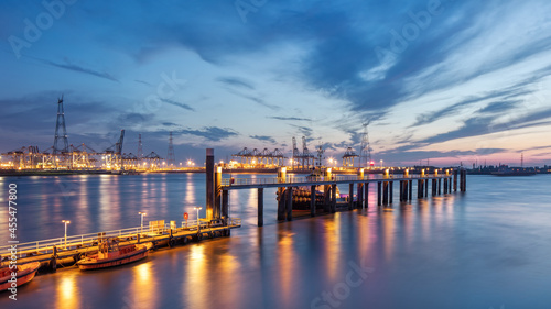 Pier in river Scheldt with container terminal on background at twilight, Port of Antwerp, Belgium.