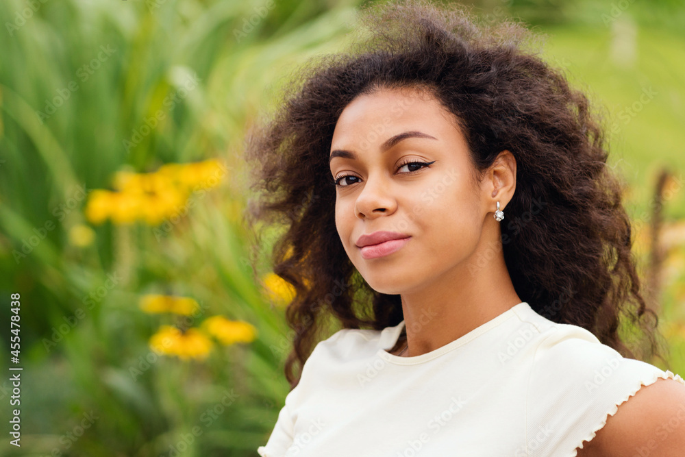 Race Black Woman Looking To Camera Smiling. African american Female with afro hairstyle city park. Dark skinned Woman in green nature background. Soft focus. fashion style Stock Photo