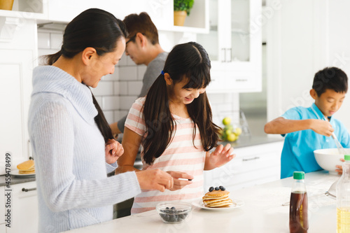 Happy asian parents with son and daughter preparing breakfast in kitchen