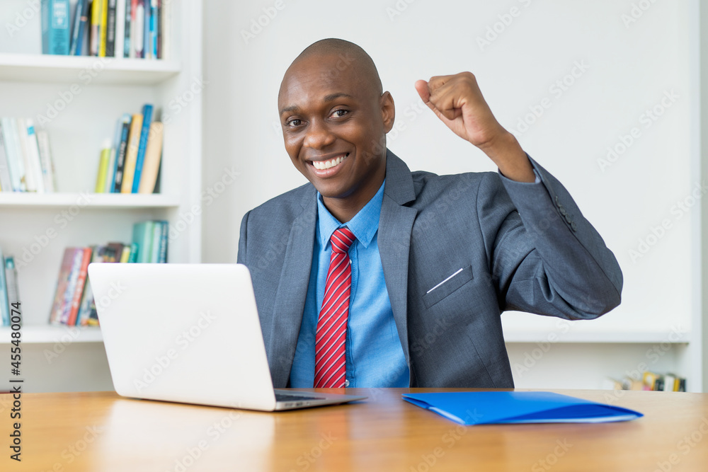 Cheering african american businessman at computer Cheering african american businessman at computer