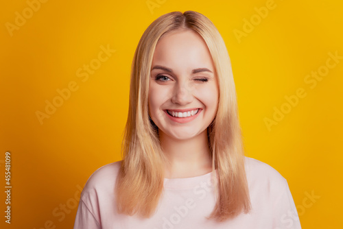 Portrait of coquette lovely lady blink eye toothy beaming smile on yellow background © Tetiana