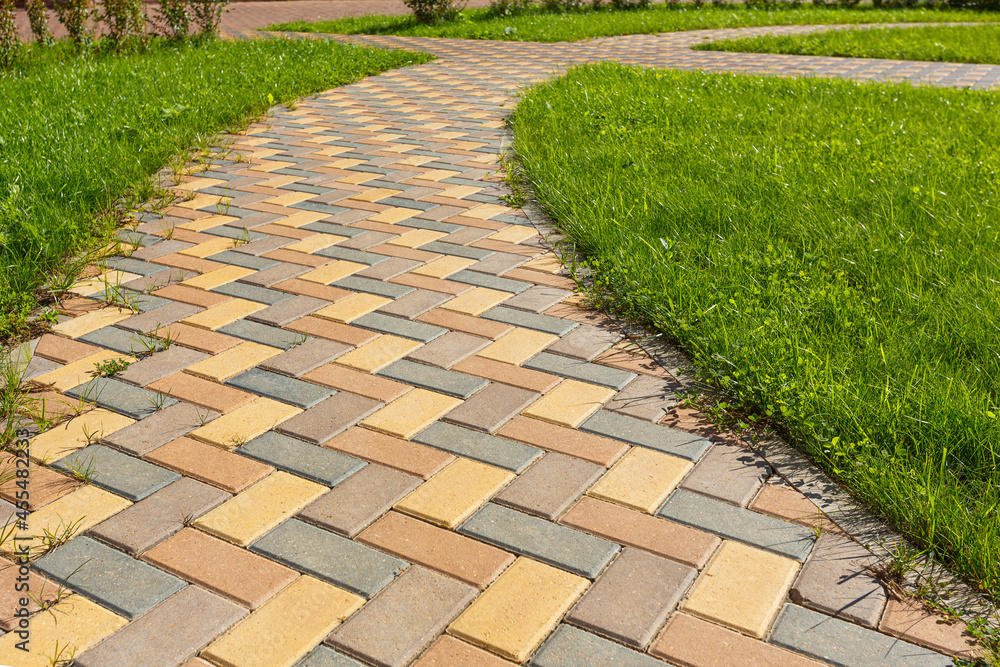 The pedestrian path paved with variegated multi-colored tiles forms a ...