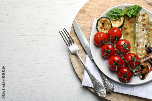 Delicious grilled vegetables served on white wooden table, top view. Space for text