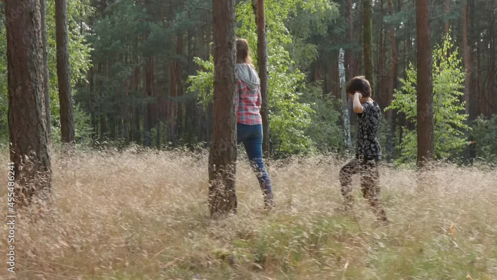 A woman and a boy are walking in the forest between the trees A woman and a boy are walking in the forest between the trees