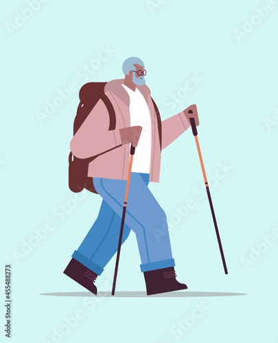 senior african american man hiker traveling with backpack and sticks for walk nordic walking active old age concept