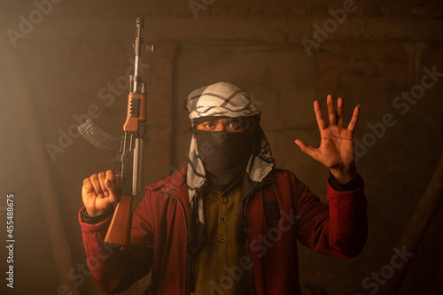 Canvas Print Militant or Gangster with face cover and gun in hand surrendering by putting hands up
