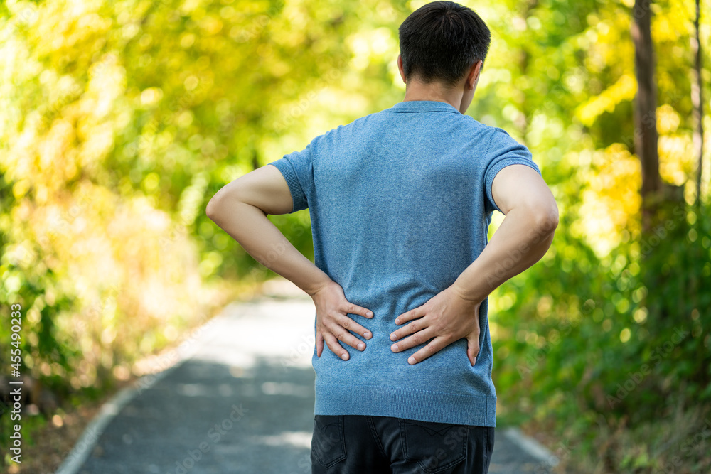 Back pain when walking outdoors, man with kidney inflammation on nature background Back pain when walking outdoors, man with kidney inflammation on nature background