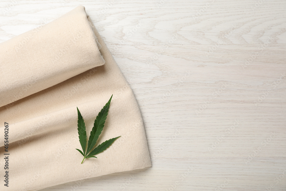 Hemp cloth with green leaf on white wooden table, top view. Space for text Hemp cloth with green leaf on white wooden table, top view. Space for text