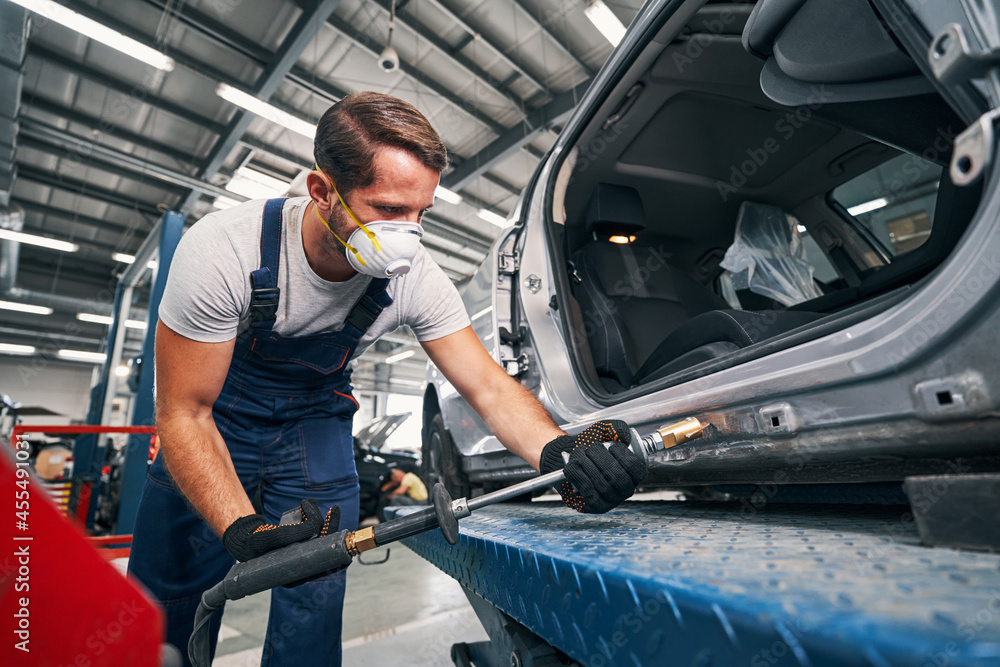Mechanic removing dents from rear part of car Mechanic removing dents from rear part of car