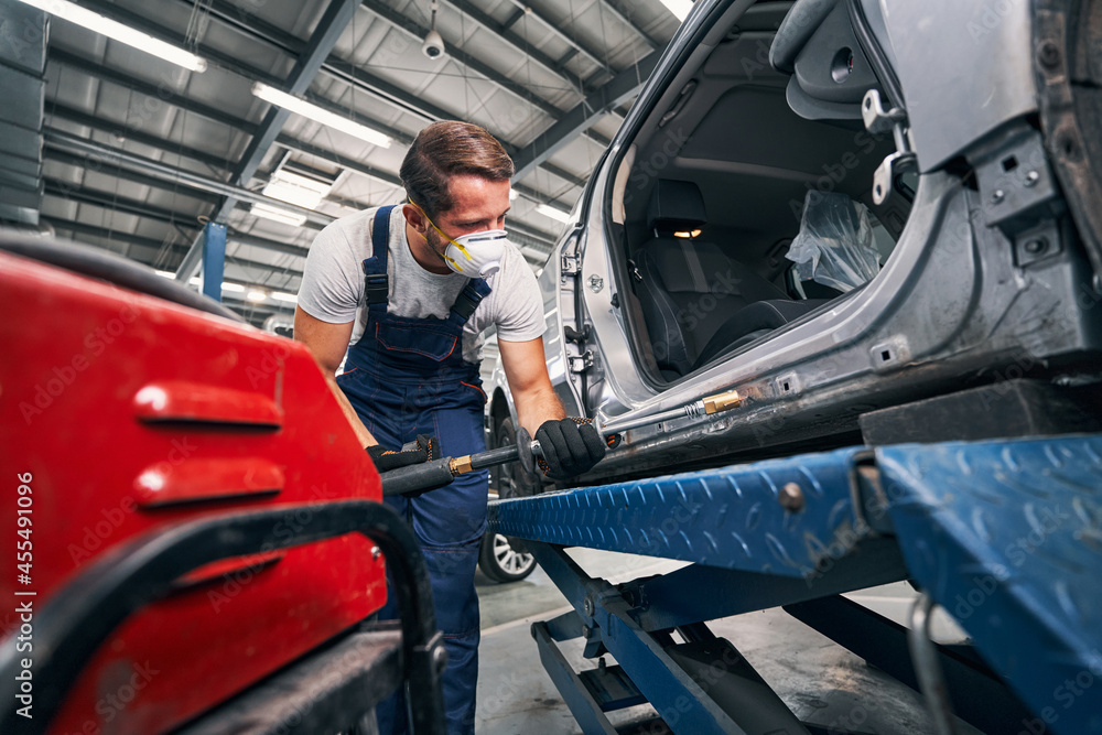 Repairman peening car with tool for removing dents Repairman peening car with tool for removing dents